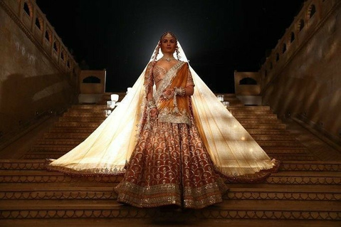 Bride descending a lit staircase with a long veil