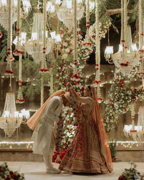 Groom greeting the bride beneath floral chandeliers